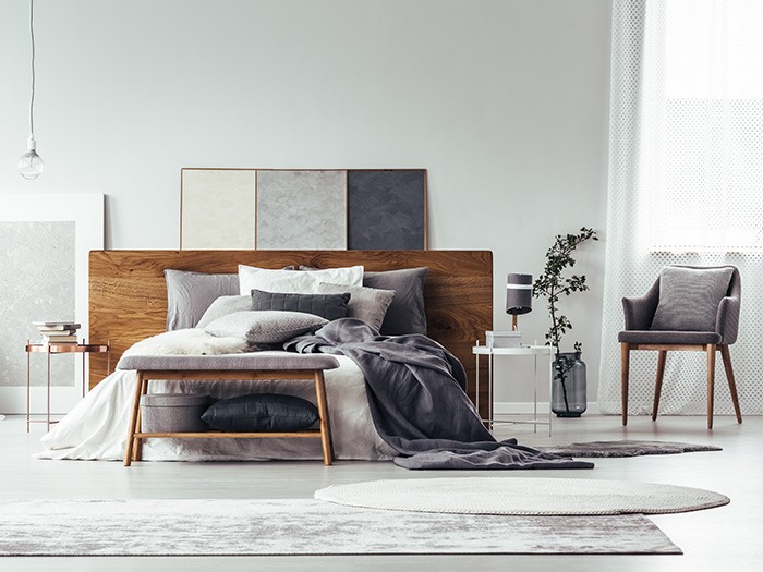 Grey toned rug under natural wood modern style bed